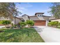 Tan two-story house with brown garage door and lush landscaping at 3238 Bailey Ann Dr, Ormond Beach, FL 32174