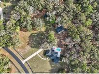 Stunning aerial view of a house with a pool and well-maintained grounds surrounded by lush trees at 7024 Sw 93Rd Street Rd, Ocala, FL 34476