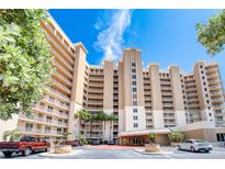 Exterior of a tall, light beige condominium building with parking and landscaping at 2403 S Atlantic Ave # 309, Daytona Beach, FL 32118