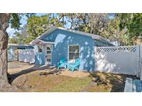 Cute blue house with a white picket fence and two teal chairs on a patio at 825 Magnolia Ave, Holly Hill, FL 32117