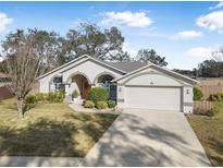 Single-story house with arched entryway, two-car garage, and well-maintained lawn at 92 Spinnaker Cir, South Daytona, FL 32119