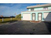 Ground level view of a teal colored building with attached garage and entrance at 2850 Ocean Shore Blvd # 8, Ormond Beach, FL 32176