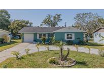 Cute teal house with a well-manicured lawn and circular flowerbed at 328 Dubs Dr, Holly Hill, FL 32117