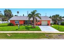 Charming single-story home with vibrant coral exterior, well-manicured lawn, and inviting curb appeal at 100 Lynnhurst Dr, Ormond Beach, FL 32176