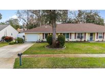 Charming single-story home featuring a well-manicured lawn, red shutters and an attached garage at 1054 W Samms Ave, Port Orange, FL 32129