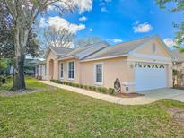 Charming single-story home with manicured lawn, mature tree, and two car garage at 1187 Athlone Way, Ormond Beach, FL 32174