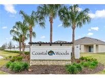 Coastal Woods community entrance sign featuring lush landscaping and swaying palm trees at 806 Armenia Ct, New Smyrna Beach, FL 32168