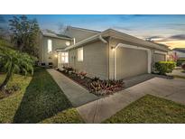 Charming exterior of a townhome featuring a well-maintained lawn, landscaping, and attached two-car garage at 25 Misners Trl, Ormond Beach, FL 32174