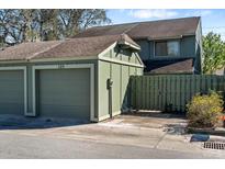 View of the detached single car garage and green wooden fence gate at the front of the townhome at 128 Pine Cone Trl, Ormond Beach, FL 32174