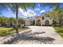Elegant home featuring a large driveway, arched entryway, lush landscaping, and beautiful windows on a sunny day at 1432 Kinnard Cir, Ormond Beach, FL 32174