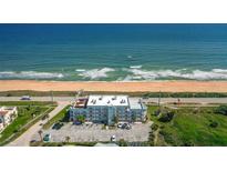 An aerial view shows the condo building, sandy beach, and ocean view at 3390 Ocean Shore Blvd # 4020, Ormond Beach, FL 32176
