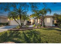 Charming single-story home with a manicured lawn, lush tropical landscaping, and a brick-paved driveway at 187 Indian Wells Ave, Kissimmee, FL 34759