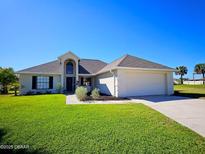 Well-maintained single-story home with a two-car garage and a lush green lawn at 14 Sea Swallow Ter, Ormond Beach, FL 32176