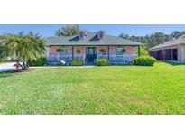 Charming single-Gathering home featuring a lush green lawn, a front porch, and lovely landscaping at 6172 Knotty Pine Ct, Port Orange, FL 32127