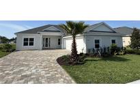 Beautiful single Gathering home with manicured lawn and charming front yard with a paver driveway and a palm tree at 1010 Megano Blvd, Deland, FL 32724