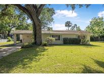 Charming single-story home featuring a well-manicured lawn and mature landscaping at 2120 Queen Palm Dr, Edgewater, FL 32141