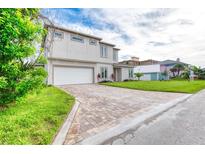 Two-story home boasts neutral colors, a brick driveway, and attached two-car garage at 32 Ocean Breeze Cir, Ormond Beach, FL 32176