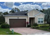Charming single-story home featuring a brown two-car garage, brick driveway, and well-maintained landscaping at 5431 Hutchinson St, Port Orange, FL 32128