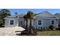 Charming single-story home showcasing a brick driveway, manicured lawn, and decorative palm trees at 1665 Lake Reserve Dr, Deland, FL 32724