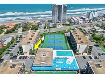 Aerial view of beachfront condo complex featuring a swimming pool, tennis courts, and ocean views at 1441 N Atlantic Ave # 211, Daytona Beach, FL 32118