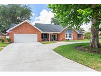 Charming single-story brick home with a two car garage, manicured lawn and inviting covered porch at 27 Winding Creek Way, Ormond Beach, FL 32174