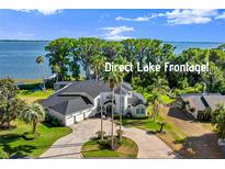 Expansive lakefront home featuring lush landscaping, circular driveway, and an attached three car garage at 3130 Indian Trl, Eustis, FL 32726