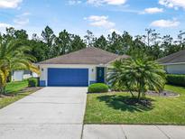 Charming single-story home with blue garage door, lush landscaping, and well-manicured lawn on a sunny day at 43 Pergola Pl, Ormond Beach, FL 32174