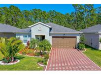 Charming single-story home with a well-manicured lawn, a brick driveway, and a two-car garage at 5635 Estero Loop, Port Orange, FL 32128