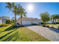 Charming single-Gathering home featuring a two-car garage, paver driveway, lush lawn, and swaying palm trees at 324 Coral Reef Way, Daytona Beach, FL 32124