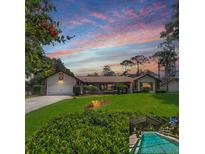 Charming single-story home featuring a well-manicured lawn, mature trees, and an inviting screened-in pool at 75 Knollwood Estates Dr, Ormond Beach, FL 32174