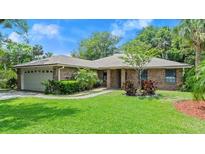 Charming single-story brick home with well-manicured lawn, mature trees and a two car garage at 912 Fruitwood Pl, Port Orange, FL 32127