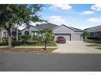Charming single-story home with a well-manicured lawn, mature trees, and a three-car garage on a sunny day at 117 Hagge Dr, Daytona Beach, FL 32124