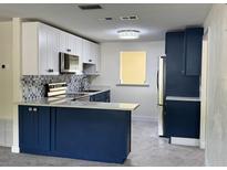 Modern kitchen featuring blue lower cabinets, white upper cabinets, and stainless steel appliances at 127 Mason Park Dr, Daytona Beach, FL 32117