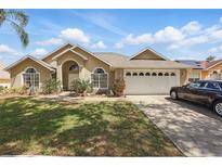 Inviting one-story home with a well-manicured lawn, arched windows, and an attached two-car garage at 1956 Southern Dunes Blvd, Haines City, FL 33844