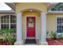 Charming red front door with decorative wreath, flanked by classic columns and lush landscaping at 1465 Admrial Nimitz Ave, Daytona Beach, FL 32124
