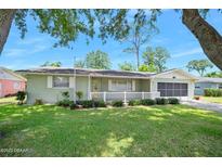 Charming single-story home featuring a well-maintained lawn, landscaping, and a screened garage at 241 Sanchez Ave, Ormond Beach, FL 32174