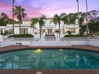 Elegant white home featuring a pristine swimming pool and meticulous landscaping, creating a serene outdoor oasis at 37918 N County Road 44A, Eustis, FL 32736