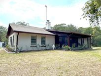 Charming single-story home with a screened porch, chimney, and landscaped flowerbeds under a cloudy sky at 486 S Us Highway 1, Oak Hill, FL 32759