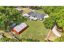 Spacious property featuring a pool, red barn, and lush greenery at 5865 Ross Creek Rd, Lakeland, FL 33810