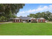 Charming single-story brick home with a well-manicured lawn and mature trees at 5865 Ross Creek Rd, Lakeland, FL 33810