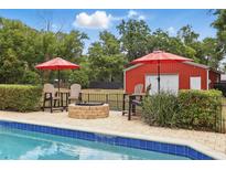 An inviting backyard oasis featuring a pool, fire pit and a charming red outbuilding with plenty of room for outdoor enjoyment at 5865 Ross Creek Rd, Lakeland, FL 33810