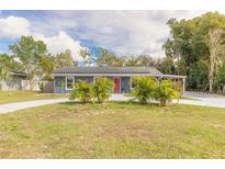 Charming home exterior with lush green lawn, solar panels, and a vibrant red front door at 991 Dawson Dr, Deltona, FL 32725