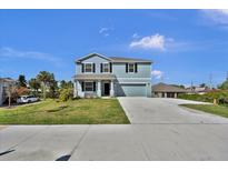 Two-story home features a large driveway, well-manicured lawn, and blue siding against a bright blue sky at 3828 S Atlantic Ave, Daytona Beach, FL 32118