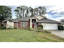 Charming single-story brick home with a well-manicured lawn and beautiful landscaping at 16 Hunt Master Ct, Ormond Beach, FL 32174