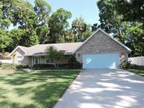 Charming single-story brick home with a well-manicured lawn and mature trees providing ample shade at 543 Sandy Oaks Blvd, Ormond Beach, FL 32174