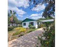 Charming home with green trim, a landscaped yard and long driveway leading up to the carport at 741 Ellen St, Daytona Beach, FL 32114