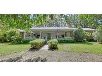 Charming single-story home with a welcoming front porch, beautiful landscaping, and an American flag at 3720 Willow Ave, Deland, FL 32720