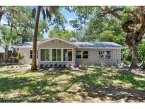 Charming single-story home featuring mature trees, lush green lawn and a cozy enclosed porch at 4901 Sailfish Dr, Ponce Inlet, FL 32127