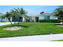 Well-maintained home with lush green lawn, mature palm trees, and a charming front porch at 13 Sunrise Ave, Ormond Beach, FL 32176