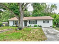 Charming single-story home with a white brick exterior, well-maintained lawn, and mature shade trees at 2101 Almond St, Orange City, FL 32763